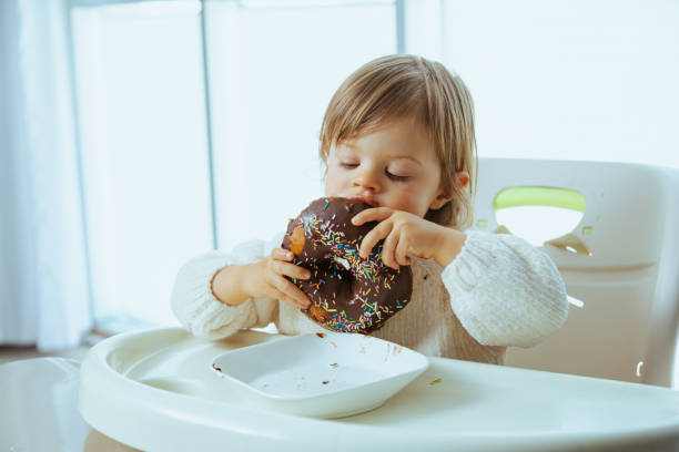 Cute toddler eats donuts with chocolate stock photo
