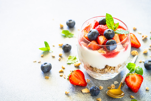 Parfait with cream or yogurt, jam and fresh berries in the glass jar. Healthy summer dessert.