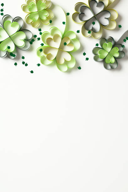 istock St Patrick's Day four leaf clover paper art on white vertical background. 2013446260