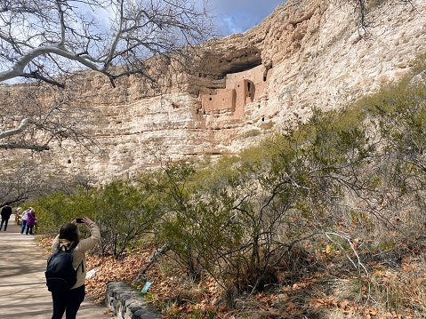 Montezuma Castle, Arizona, United States - February 3rd, 2024: A woman taking a photo Montezuma Castle at the National Monument, a set of well-preserved dwellings located in Camp Verde, Arizona, USA.