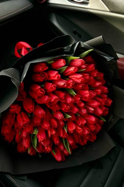 istock A large bouquet of bright red tulips on a red car 2013484014