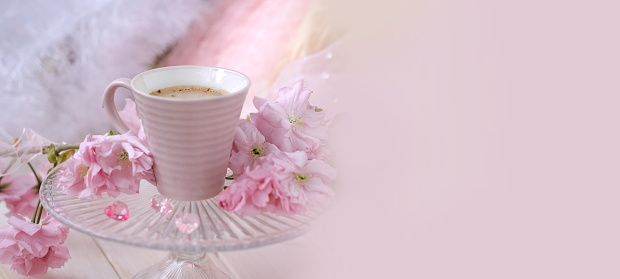 cup with drink coffee cappuccino, hot chocolate with milk, pink sakura flowers, caffeine improves functioning of human brain, stimulates nervous system, health benefits and harms, copy space, banner