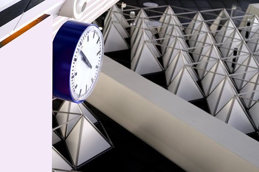 large modern clock in airport on a beautiful background, geometric shapes on the ceiling, concept delay, flight cancellation, arrival time, don't miss your flight, Frankfurt, Germany
