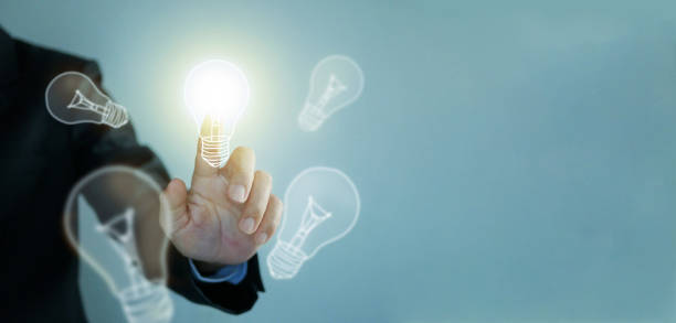 Idea concept. Lightblub is on as a symbol of innovation, inspiration, solution, and creativity. Hand touches an illuminated light bulb. Copy space and background  for creative idea and thinking