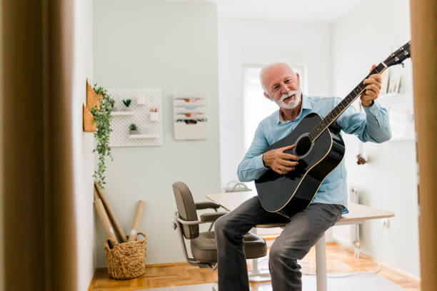 istock Senior male playing guitar at home office 2013545294