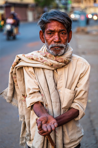 Poor Indian man standing on a street and asking for support.