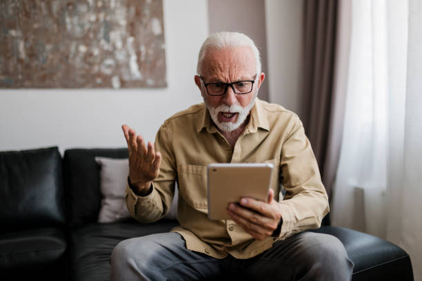 istock Angry Elderly man grandfather using digital tablet, searching web, loading feed, social media. Communication with children, grandchildren on lockdown 2013557605
