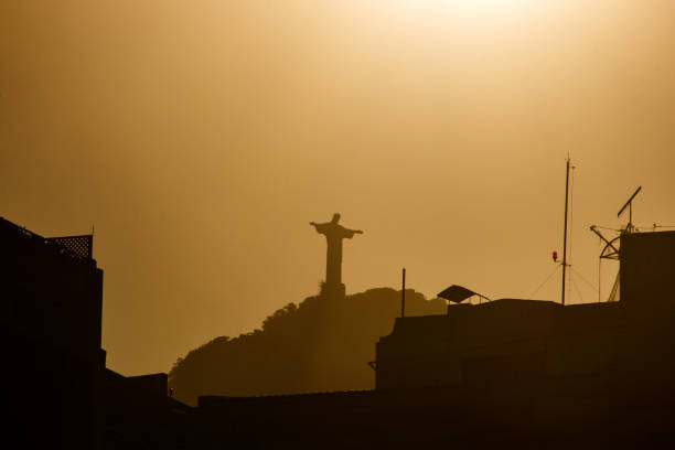 sun setting with Christ the Redeemer in Rio de Janeiro, Brazil - July 6, 2023: Sunset with the statue of Christ the Redeemer seen from the Copacabana neighborhood in Rio de Janeiro.