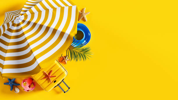 istock Beach umbrella with summer accessory and luggage on vibrant yellow background with copy space. Ready for summer vacation concept. 2013659034