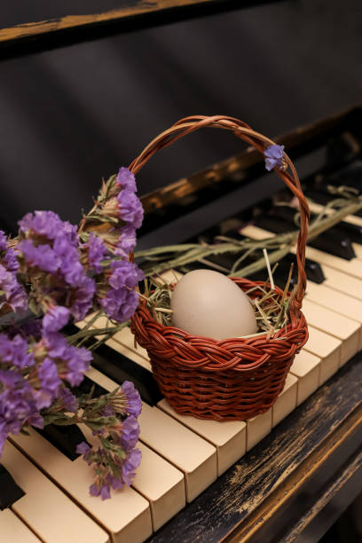 istock Easter composition with a small basket with one egg on an old piano decorated with purple statice flowers 2013687671