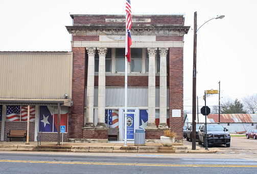 The town hall of Italy, Texas with a flags in front of it and police cars beside it