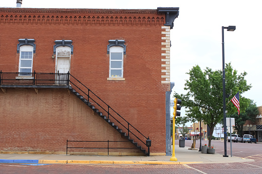 The side of a historic building with a fire escape staircase in Russell, Kansas