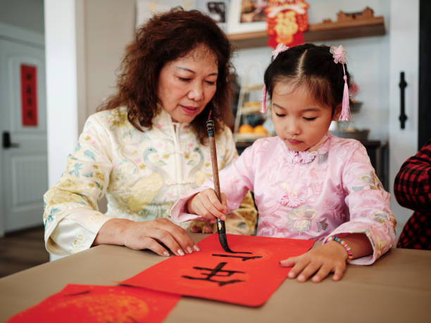 chinese family practicing calligraphy for chinese new year fai chun (auspicious messages) - chinese script text calligraphy grandmother stock-fotos und bilder