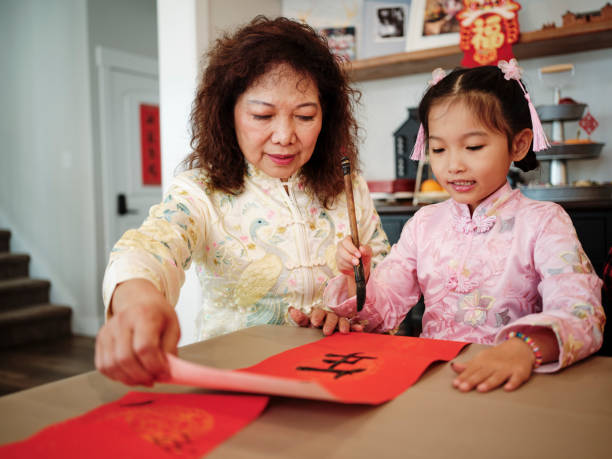 chinese family practicing calligraphy for chinese new year fai chun (auspicious messages) - chinese script text calligraphy grandmother stock-fotos und bilder