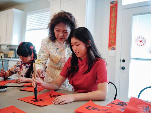 chinese family practicing calligraphy for chinese new year fai chun (auspicious messages) - chinese script text calligraphy grandmother stock-fotos und bilder