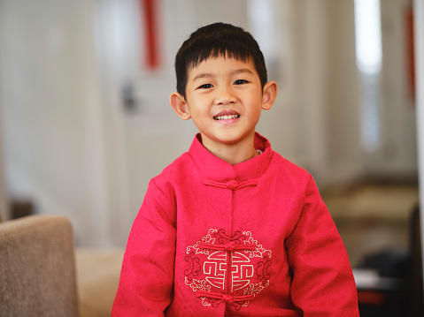 A portrait of a Chinese boy in a home, wearing traditional clothing.