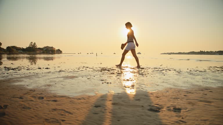 SLO MO Shot of Woman Walking on Shore at Beach and Enjoying Sunset During Vacation