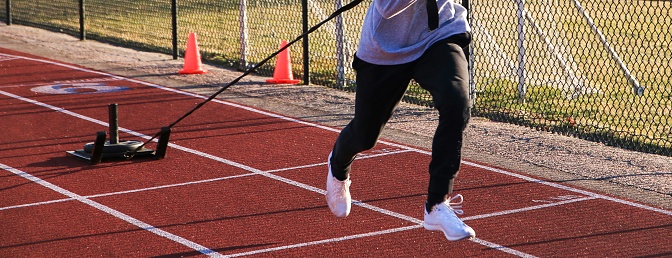 High school boy pulling a sled with weight on a track