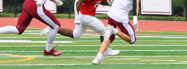 istock Football running back trying to avoid being tackled by two defenders 2013784231