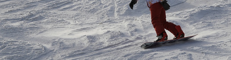Young woman snowboarder in motion on snowboard in mountains on the slopes
