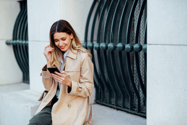 istock Woman looking at her phone while sitting in public space outside. 2013811815