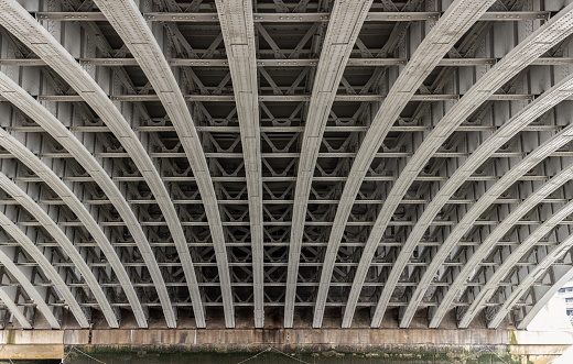 View of Structure and beams under the Curved steel Bridge. Framework metal arches girder construction Underneath of Blackfriars Bridge, Riveted steel beams supporting bridge span, Space for text, Selective focus.