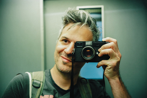 Photographer taking a mirror selfie with an old analog camera.