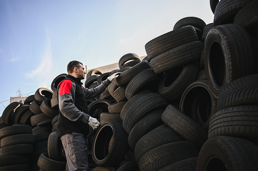 man working at scrap tires in the recycling bin.