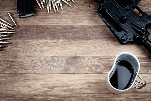 assault rifle and cup of coffee on wooden table photo