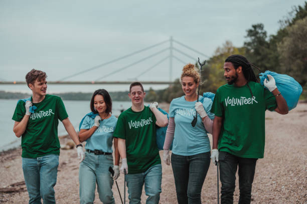 istock Five volunteers in uniforms carrying trash  and walking by the river 2013962477