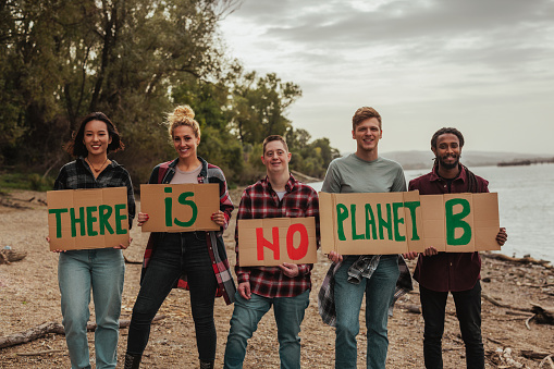 Group of multiethnic volunteers holding a placard with a message on earth day by the river