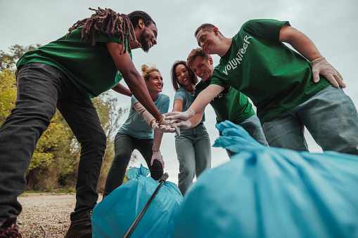 Group of inclusive, Caucasian, male and female, multiethnic volunteers that clean trash cheering after a well done job