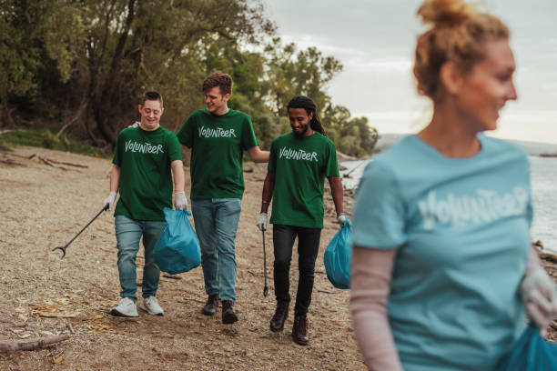 istock Volunteers in uniforms talking and cleaning the beach by the river 2013962933