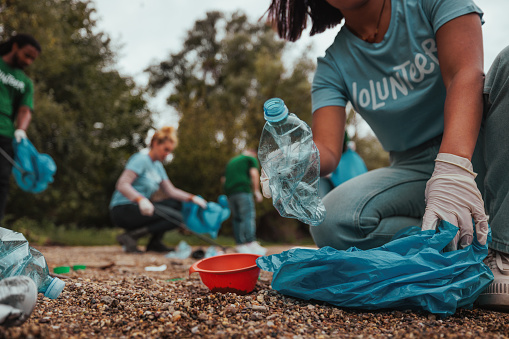 Beautiful shot of woman s hands putting a plastic bottle in a plastic bag while volunteering on earth day