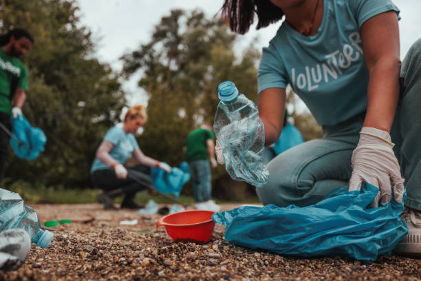 Shot of a woman putting plastic bottle in a plastic bag Beautiful shot of woman s hands putting a plastic bottle in a plastic bag while volunteering on earth day earth day clean up stock pictures, royalty-free photos & images