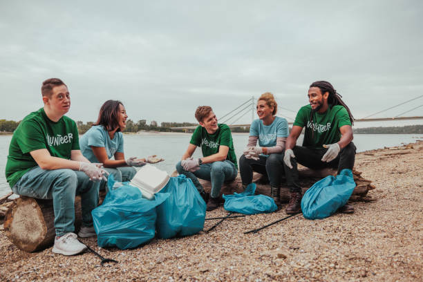 istock Five happy volunteers in uniforms sitting by the river 2013963456