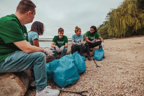 istock Five volunteers in uniforms sitting by the river after hard work 2013963469