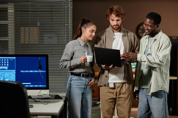 istock Young people using laptop in office at night 2013971139