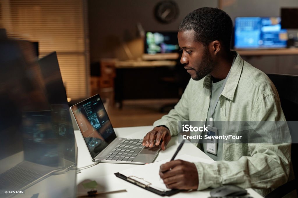 Black Young Man Using Computer And Taking Notes Stock Photo - Download ...