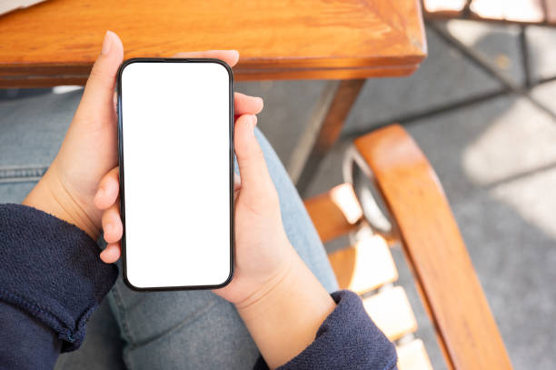 istock A woman using her phone while relaxing in a cafe. A smartphone white-screen mockup in a woman's hand 2014070313