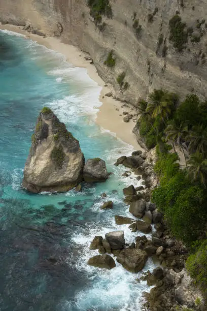 Scenic rugged coastline of sea stacks rocks, white sand beach and breaking waves  on a tropical Nusa Penida island