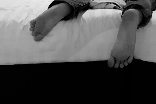 a pair of feet on the bed, sleeping on his stomach
