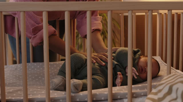 Mother Putting Baby to Sleep at Crib