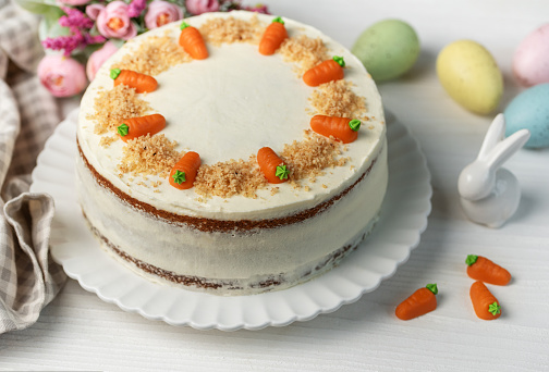 Homemade Easter carrot cake made with walnuts, iced with cream cheese. Sweet dessert.  Plate with delicious carrot cake