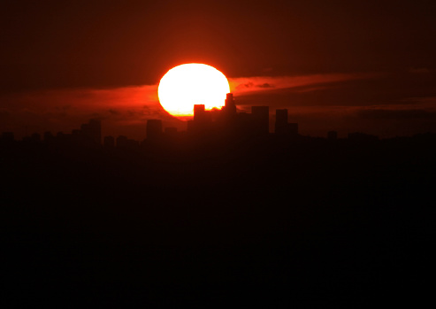 Telephoto of solar disc setting on the skyline of downtown Los Angeles as seen from South Hills Park, Glendora, California.