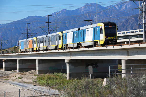 Metro Gold Line over San Gabriel River Bridge in Irwindale, California, with mountain slopes in background.