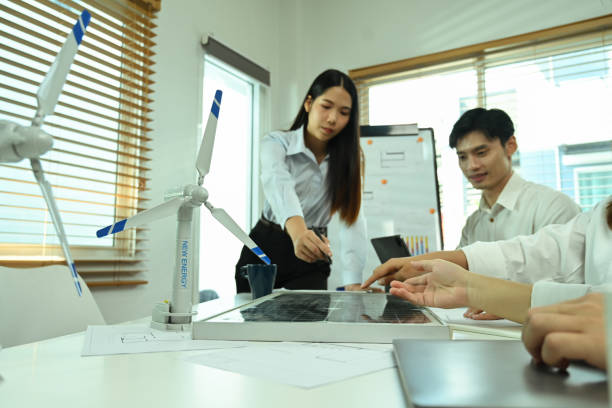 istock Team of eco engineers having a discussion while working with wind turbine models and solar panel at office 2014435483