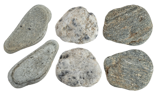 Macro photo of gray pebble stone on top of smaller stones. There are black abstract lines on big stone. Shot in studio with a full frame mirrorless camera.