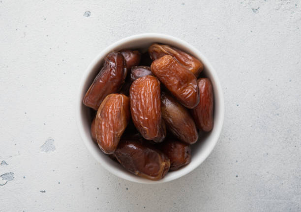 istock Dried sweet organic dates in ceramic bowl on light background.Top view. 2014471402