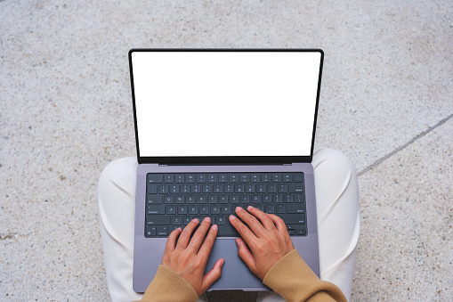 Top view mockup image of a woman working and typing on laptop computer with blank screen